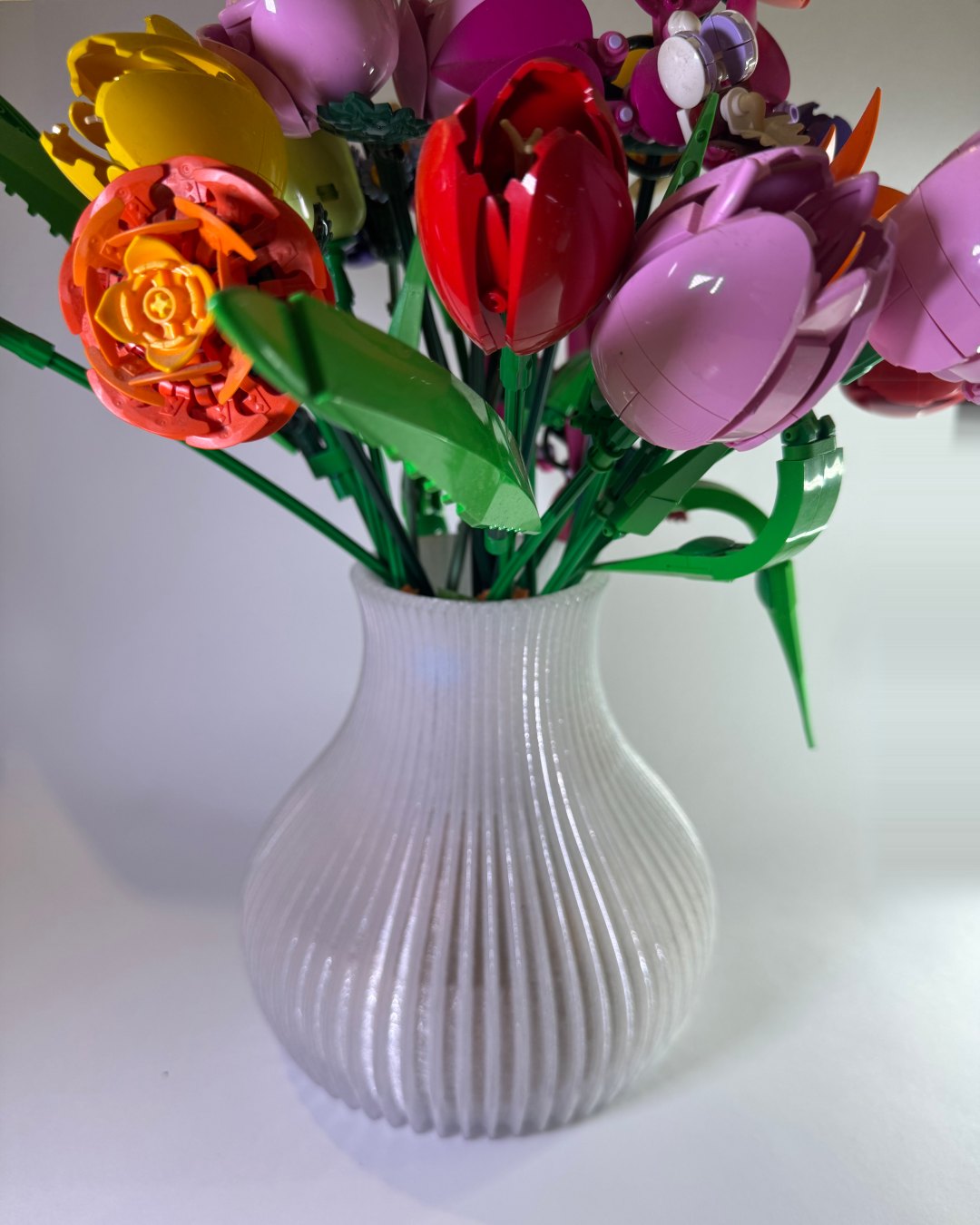 Florero blanco con textura ondulada, fotografiado con flores de construcción.
